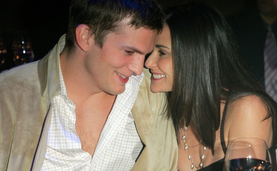 Ashton Kutcher and Demi Moore embrace and laugh during an event.