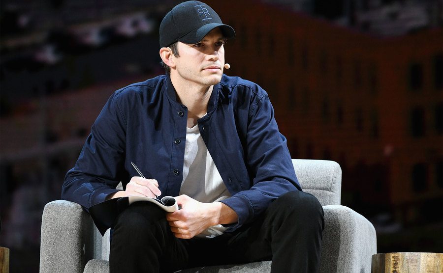 Ashton Kutcher speaks onstage during a conference. 
