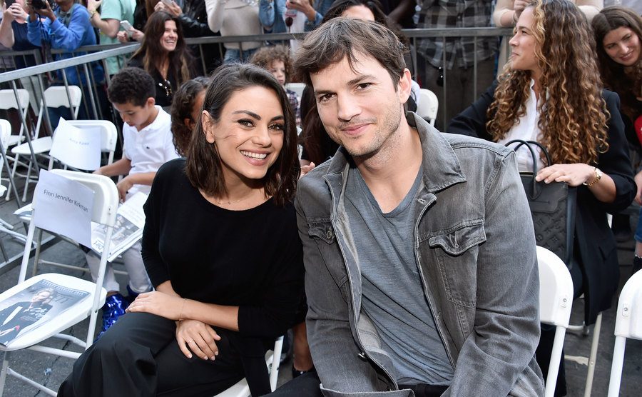 Kunis and Kutcher smile for a picture during an event. 