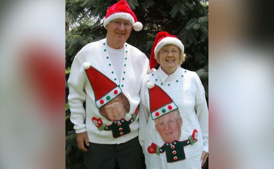 An old couple is wearing each other as elves on their sweaters. 