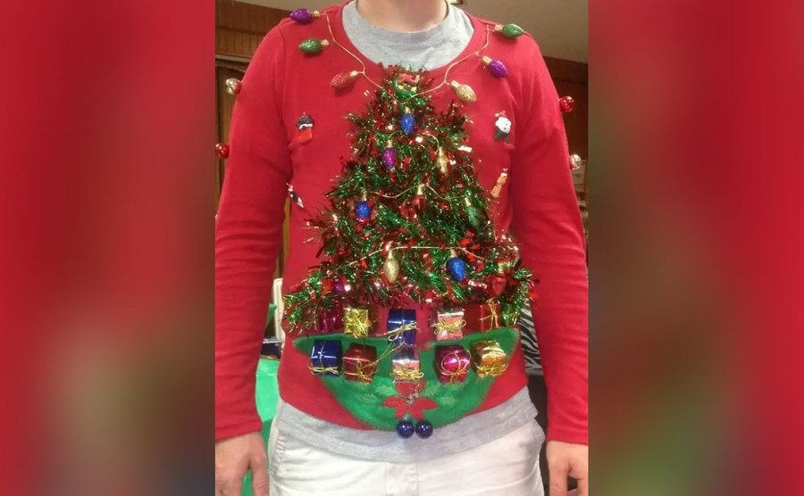 A sweater with a very messy and overdecorated Christmas tree on it. 