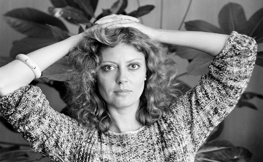 Susan Sarandon poses with her hands on her head. 