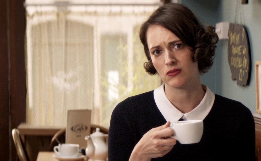 Phoebe Waller-Bridge, as Fleabag, drinks tea in her coffee shop. 
