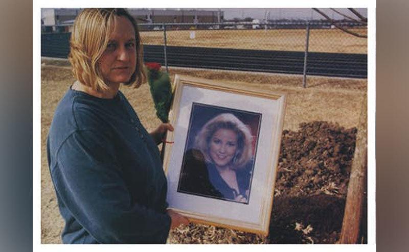 Adrianne’s mother holds up a framed photo of her daughter. 