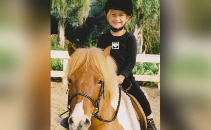 A young Bella Hadid is riding a pony. 