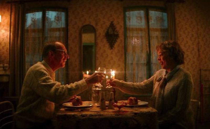 Christopher and Susan’s characters are having dinner in a still from the film.