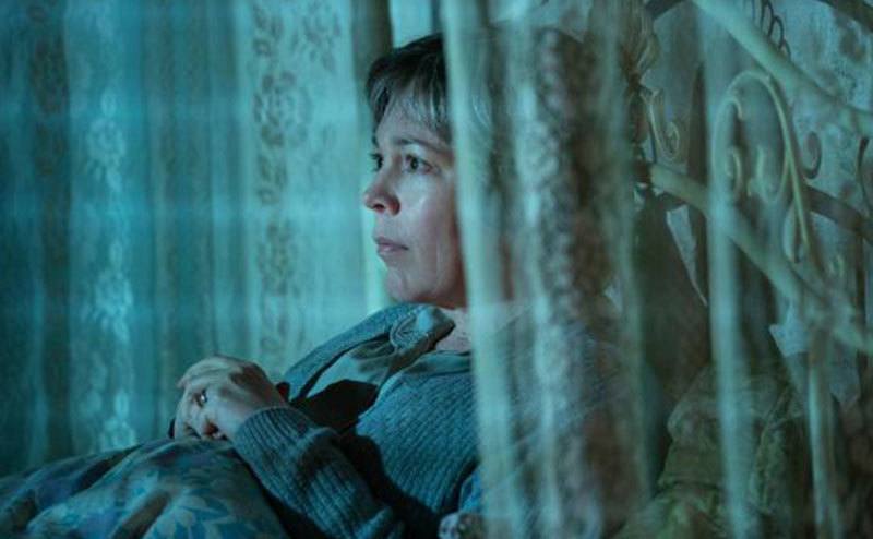 A still from Susan’s film character sitting in bed.