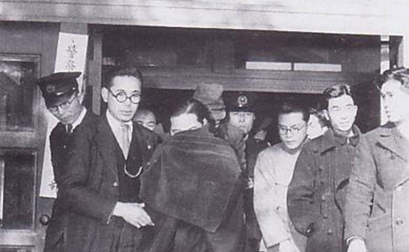 Police escort Ishikawa outside court.