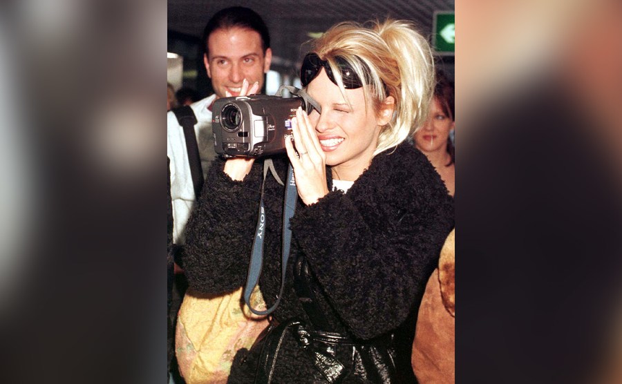 Pamela Anderson holds a video camera. 
