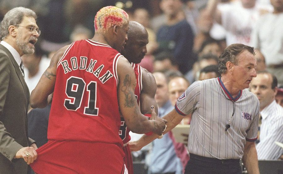Coach Phil Jackson tries to hold Rodman back as he argues with an official.