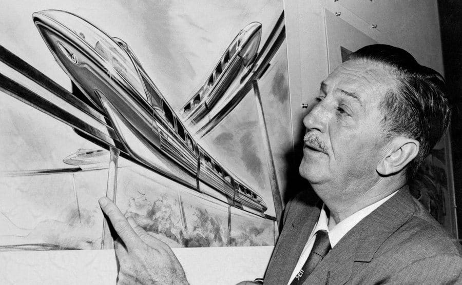 Walt Disney examines an artist's drawing of the Monorail system.