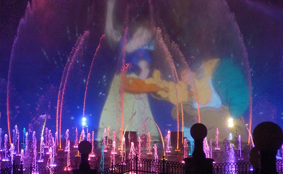 Snow White and the Seven Dwarfs are projected on the water during a show.