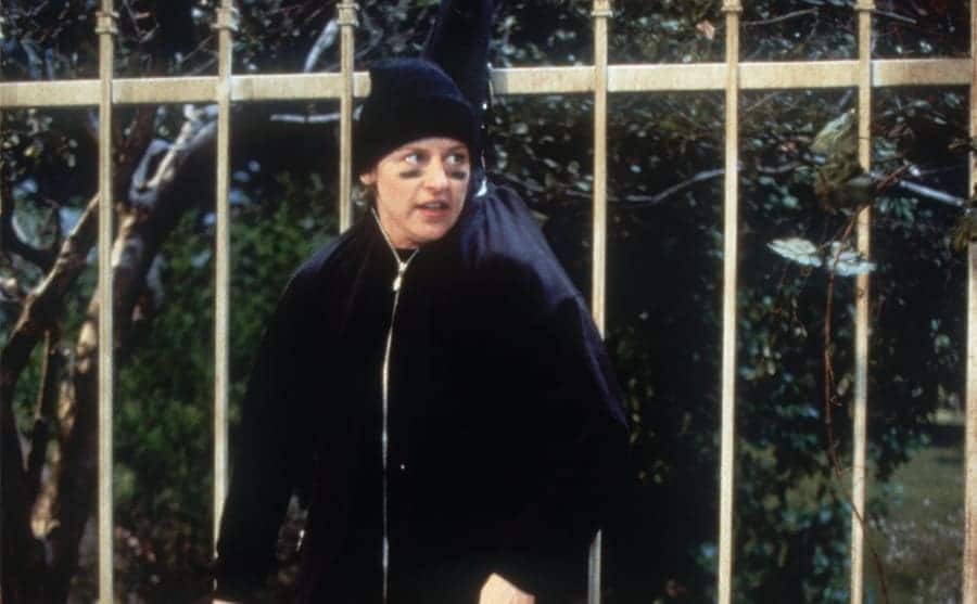 Ellen DeGeneres caught hanging from a fence by her black hoodie in an episode of Ellen 
