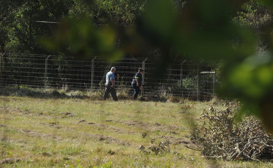An image of police investigator and forensics walking around the farm.