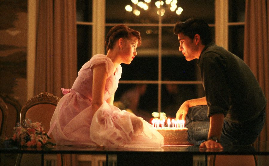 Michael Schoeffling and Molly Ringwald share a cake. 