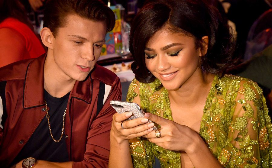 Tom Holland and Zendaya sit together at an event. 
