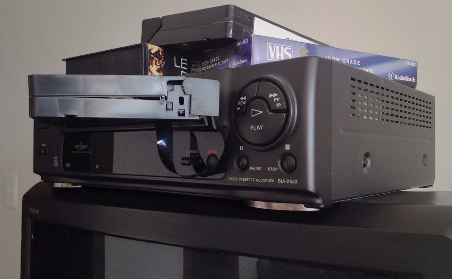 An image of an old VHS video player with videotapes.
