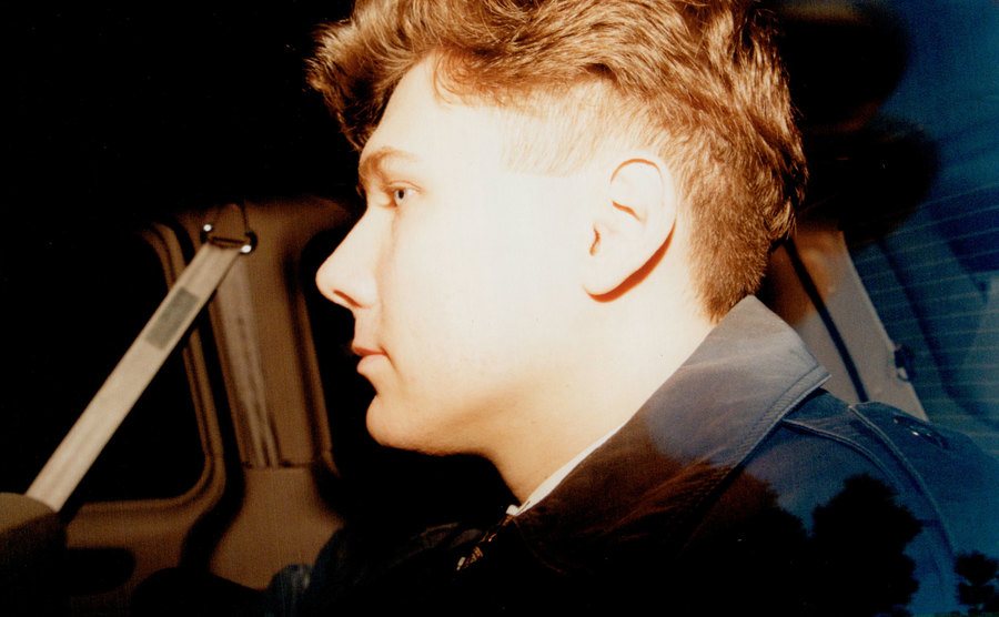 An image of Paul Bernardo sitting in the backseat of a car.
