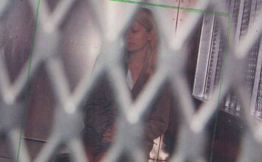 A photo of Karla Homolka handcuffed sitting inside a police car.