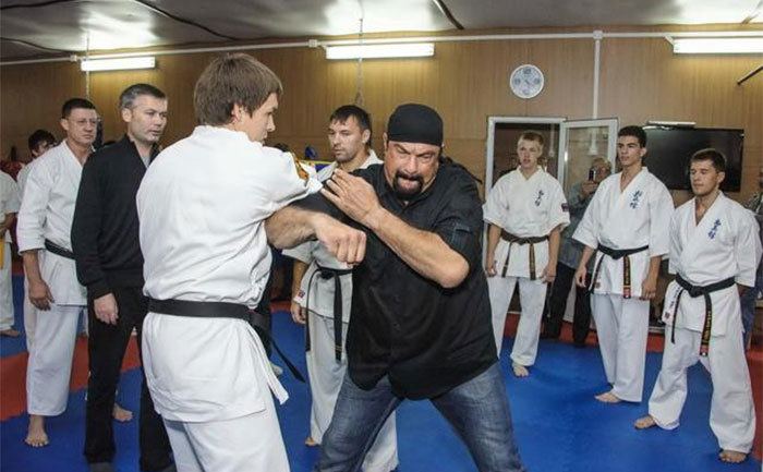 Steven Seagal is showing off his moves in a dojo. 