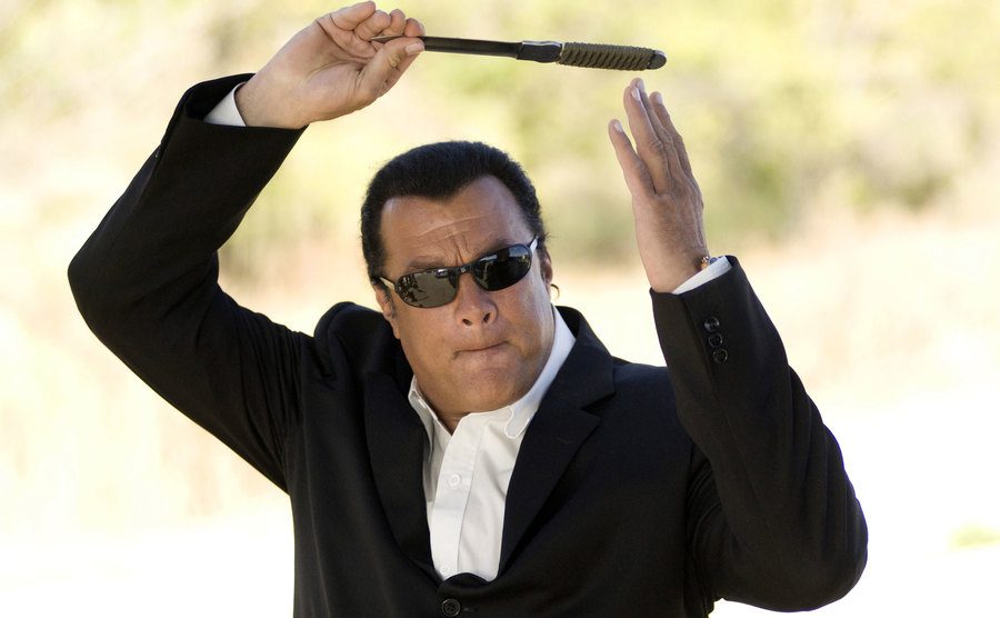 Steven Seagal throws a knife in a still from a film. 