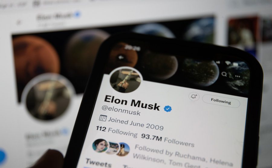 A photo illustration of a man looking at Elon Musk's Twitter account.