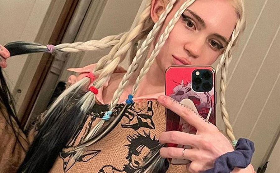 Grimes takes a picture of herself in front of a mirror.