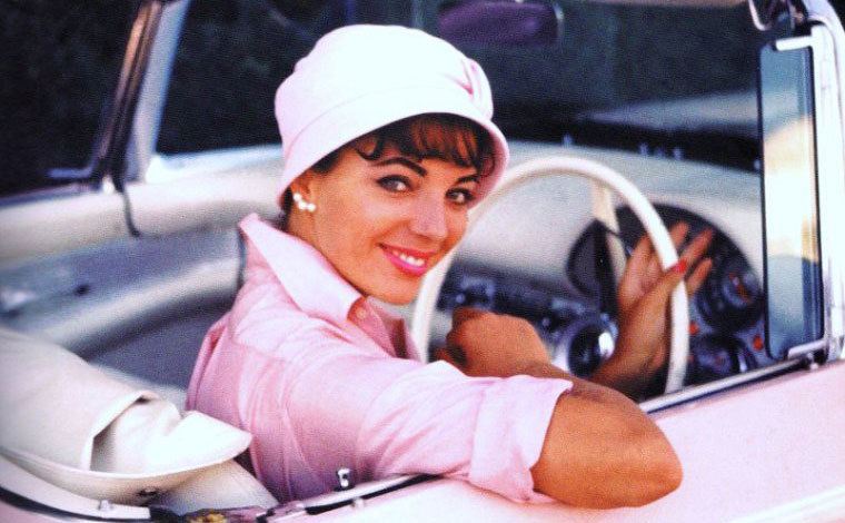 Joan poses for a photo as she sits in the driver’s seat of her pink car. 