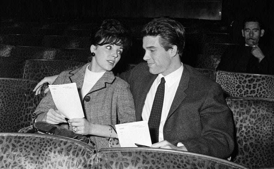 Warren Beatty and Joan Collins sit in a theater together. 