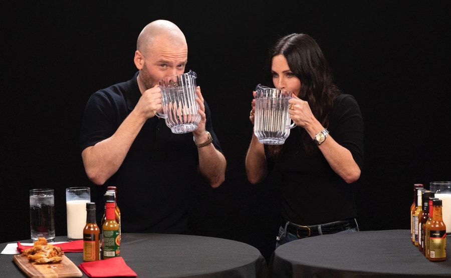 Sean Evans and Cortney Cox drink out of water pitchers. 