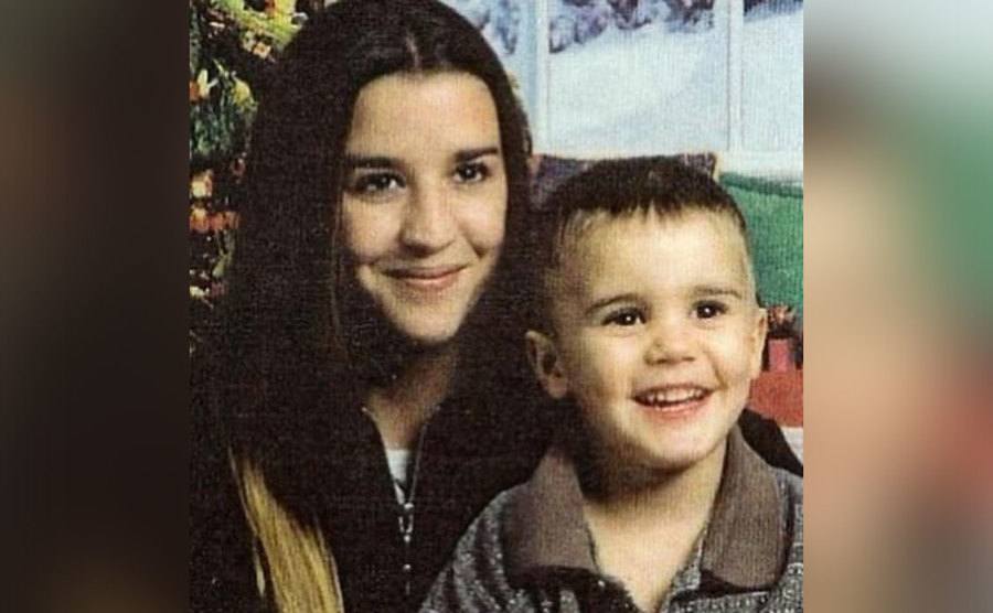Justin Bieber and a toddler poses with his mother. 