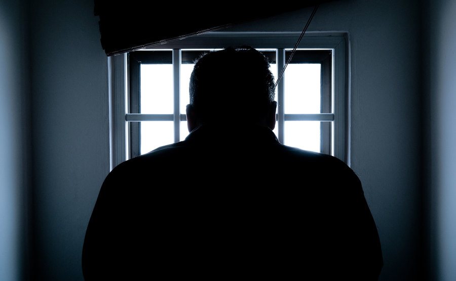An image of a man sitting in a prison cell.