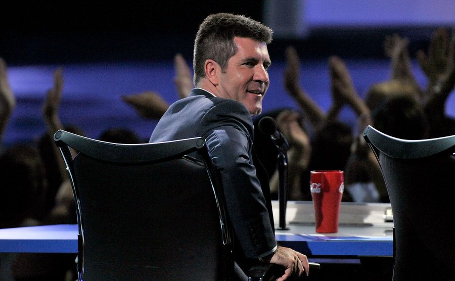 Cowell sits on stage during a season finale.