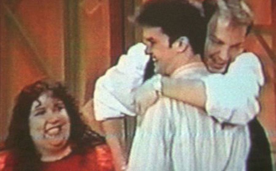 A still of Amedure hugging Schmitz on television.