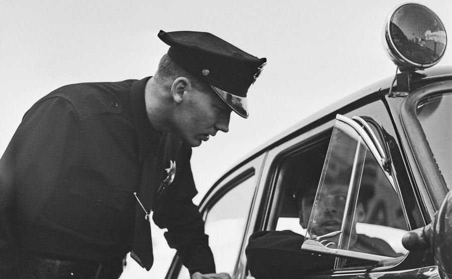A police officer chats with his colleague in a police car.