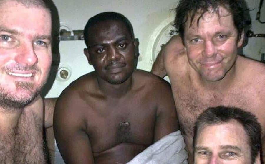 Harrison Okene poses inside a decompression chamber with members of the diving team.