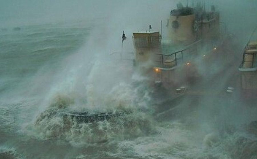 An image of a boat in the middle of a sea storm.