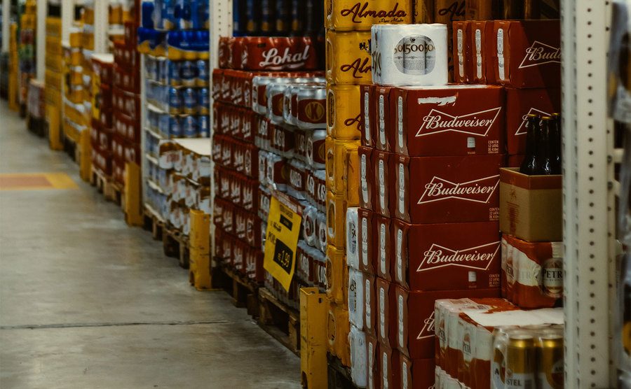 Beer cans are stacked on shelves in the store. 