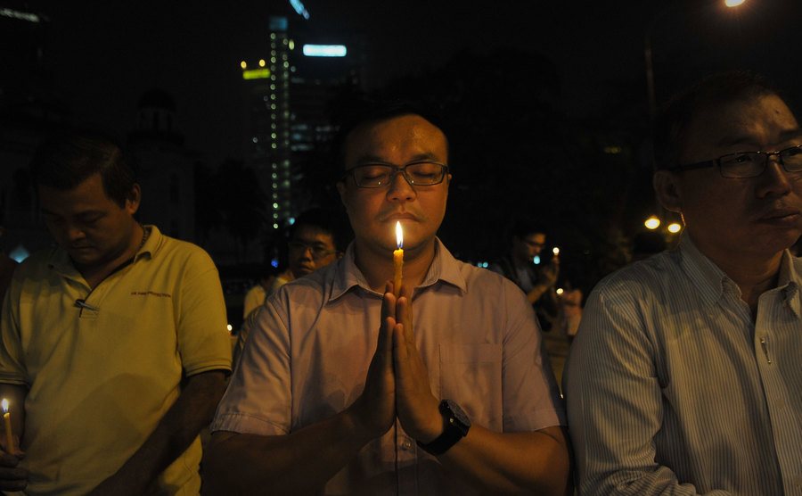 A man offers a prayer during a candlelight vigil for the flight passengers.