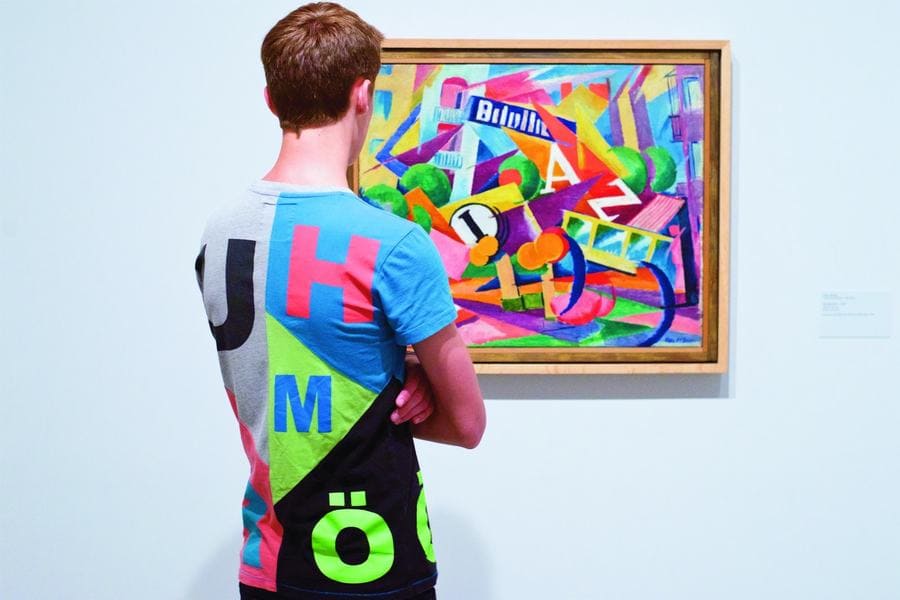 Man with a vibrant shirt standing in front of a multicolored painting