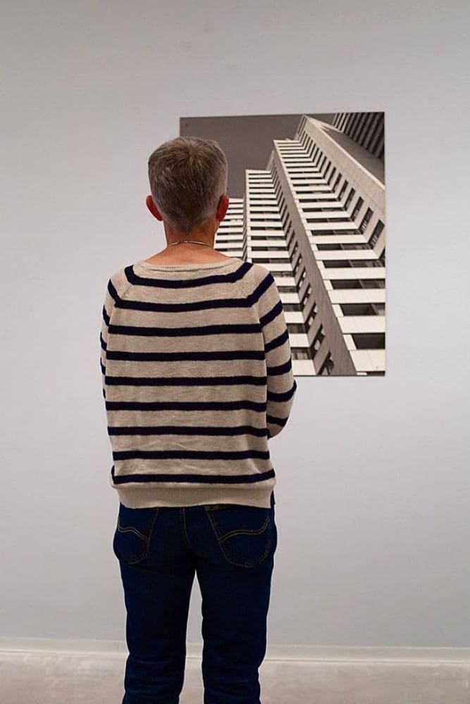 A woman in a black and white striped sweater admiring a portrait of a building that looks similar to her sweater.