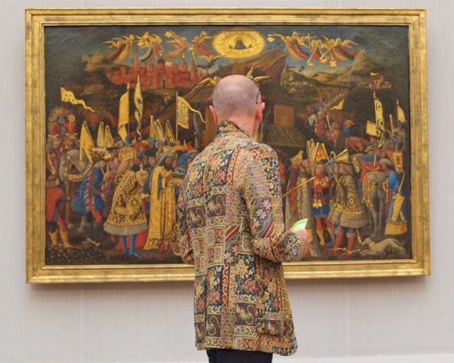 A man wearing a colorful patterned sports jacket admiring a painting with a similar concept.